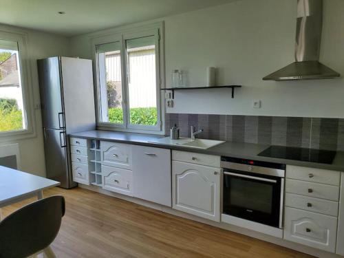 Una cocina con gabinetes blancos y un refrigerador. en Maison du Domaine (Gîte), en Chalonnes-sur-Loire