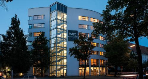 ein großes weißes Gebäude mit Licht an in der Unterkunft Victor's Residenz-Hotel Berlin Tegel in Berlin