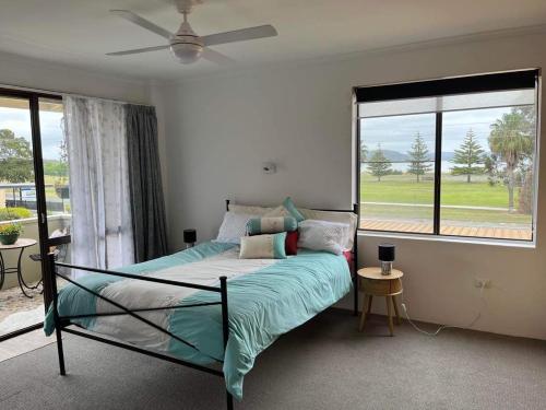 a bedroom with a bed and a large window at A Beach front Apartment in Batehaven