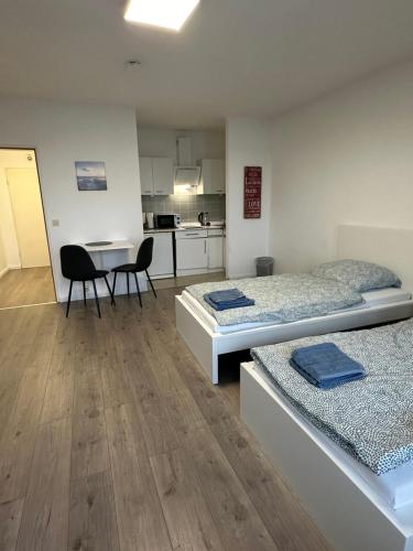Habitación con 2 camas, mesa y cocina. en Stay-Happy Flat in Halstenbek, en Halstenbek