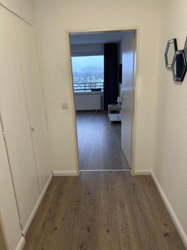 an empty hallway with a door to a room with wood floors at Stay-Happy Flat in Halstenbek in Halstenbek