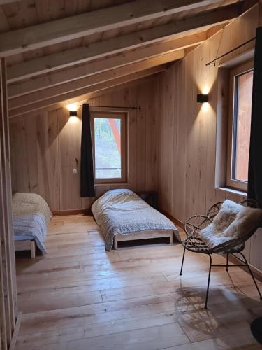 sypialnia z 2 łóżkami i krzesłem w obiekcie Lodges Clara Vallis w mieście Clairvaux-les-Lacs
