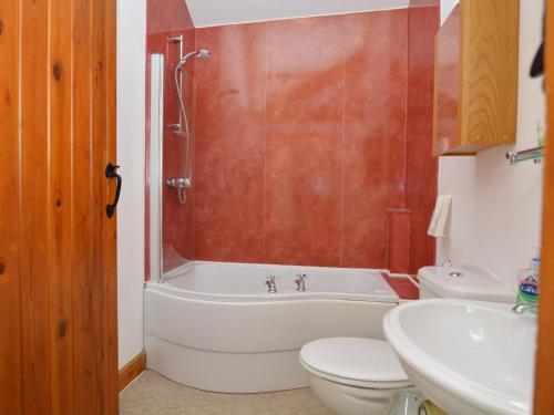 a bathroom with a tub and a toilet and a sink at 2 Bed in Sherborne FOLKI in Long Burton