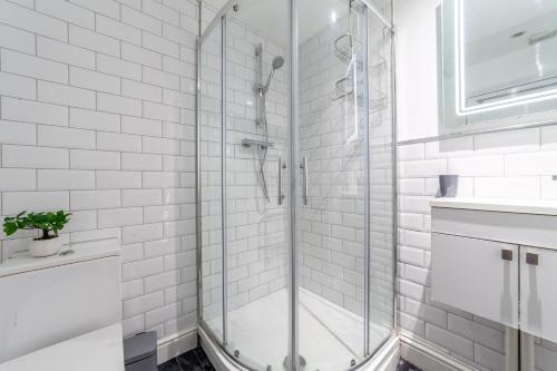 uma casa de banho com chuveiro e azulejos brancos do metro em The Richmond Apartments em Richmond upon Thames
