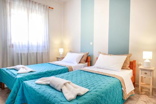 sypialnia z 2 łóżkami i ręcznikami w obiekcie Catherine Blue Suites - 4 minutes off the Beach w mieście Poros