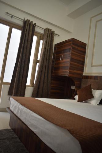 a bedroom with a large bed and windows at Chopta House Hotel and Restaurant in Sari