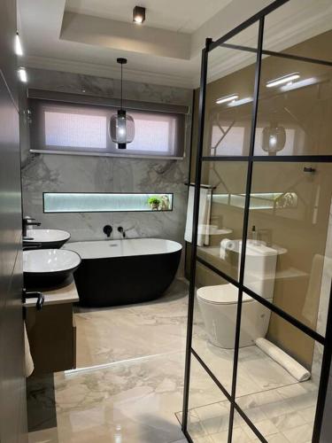 a bathroom with a tub and a toilet and a sink at Gariep Airbnb Kimberley in Kimberley