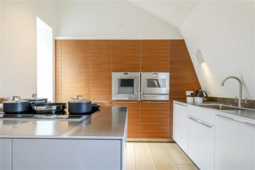 a kitchen with stainless steel appliances and wooden cabinets at Lux, Large Central Mayfair Location Flat in London