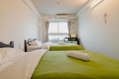 um quarto com 3 camas com verde e branco em Fukuoka Share Hotel em Fukuoka