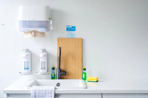 a white bathroom with a sink and a wooden organizer at Work & Stay Apartment Goch in Goch