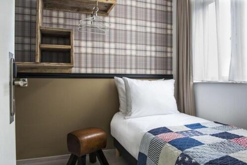 a bedroom with a bed and a stool next to a window at Max Brown Hotel Canal District, part of Sircle Collection in Amsterdam
