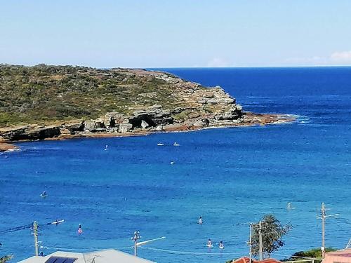 a beach with people swimming in the water at Brand NEW VIP Luxury 5/5 Star Beachside Escape in Sydney