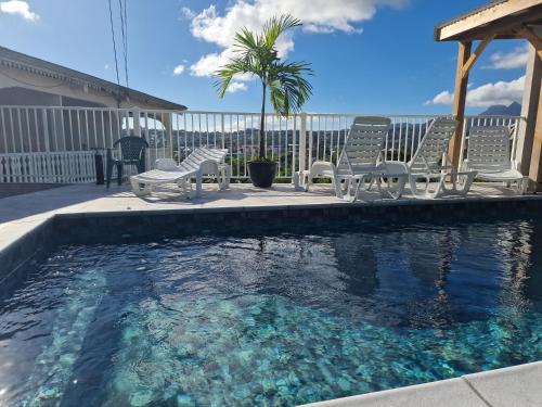 una piscina con sillas y un cenador en Hébergements La Favorite en Le Lamentin