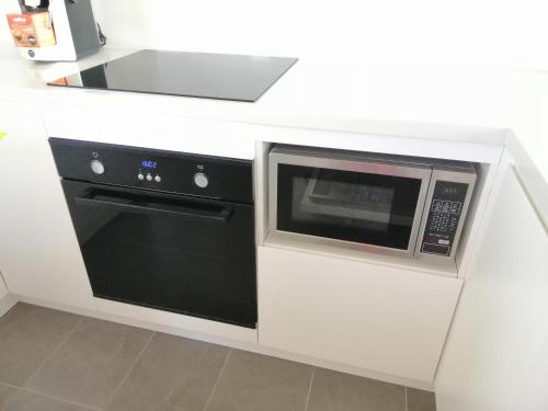 a microwave and a stove in a white kitchen at Brand NEW VIP Luxury 5/5 Star Beachside Escape in Sydney