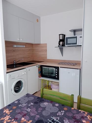 a small kitchen with a table and a microwave at Digne vallon des sources in Digne-les-Bains