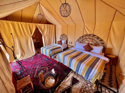 a bedroom with two beds in a tent at Desert Sahara Luxury Camp in Merzouga