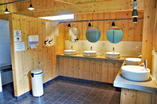 a bathroom with three sinks and three mirrors at Camping Gorishoek in Scherpenisse