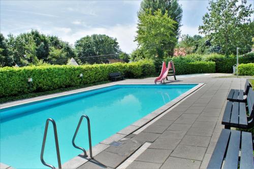 a swimming pool with two chairs in a yard at Camping Gorishoek in Scherpenisse