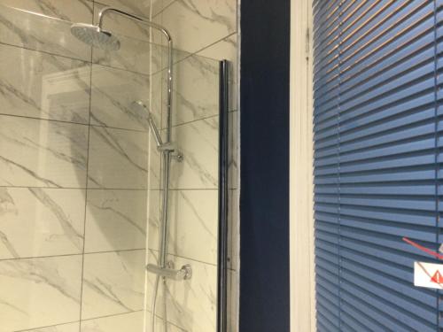 a shower with a glass door next to a window at TDM Bachelot Lettings Ltd in London