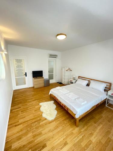 a white bedroom with a large bed and wooden floors at BioLocalia House Bucovina in Baloteşti