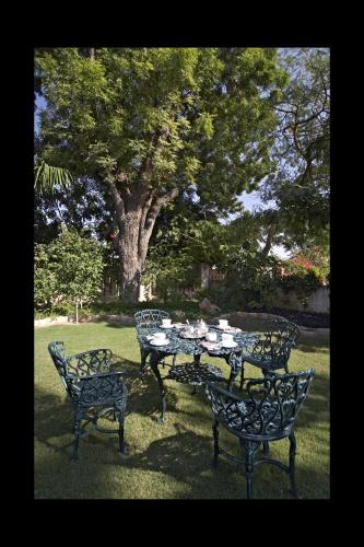 a table and four chairs in a yard with a tree at Barwara Kothi in Jaipur