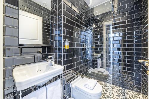 a black tiled bathroom with a sink and a toilet at Hotel Aska in Reykjavík