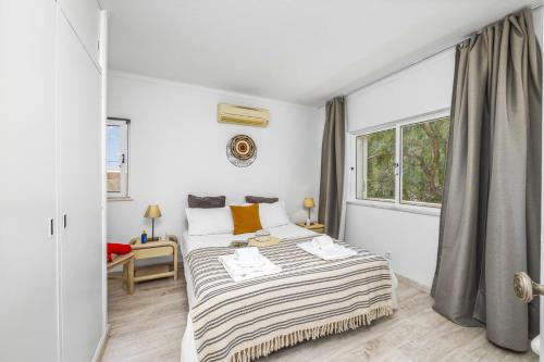een witte slaapkamer met een bed en een raam bij Villa Casa Pimenteira by Villa Plus in Lagoa