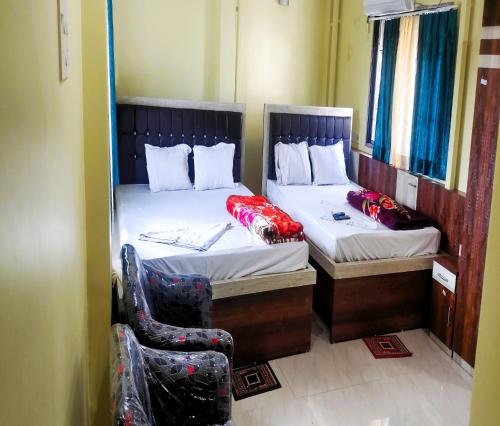 2 camas individuales en una habitación con silla en STAYMAKER Tirupati Guest House, en kolkata
