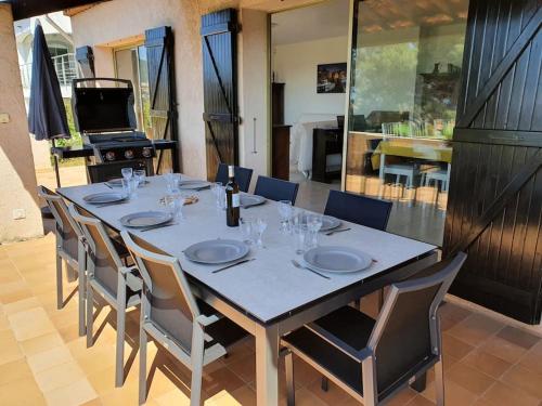 - une grande table avec des chaises et une bouteille de vin dans l'établissement Villa Horizon/Vue mer/Plages/WIFI/CLIM, à Carqueiranne