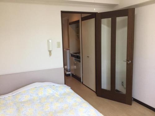 a bedroom with a bed and an open door at Business Inn Grandeur Fuchu in Fuchu
