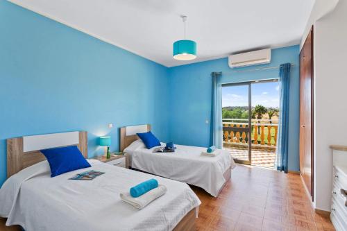 2 Betten in einem Zimmer mit blauen Wänden und einem Balkon in der Unterkunft Villa Carlos by Villa Plus in Galé