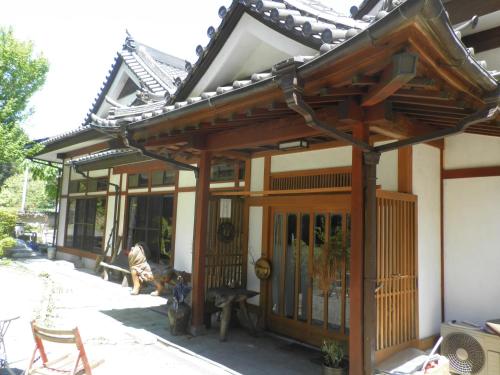 ein Haus im asiatischen Stil mit einem Tor und einer Bank in der Unterkunft COZY Inn Free Shuttle service in Nikko