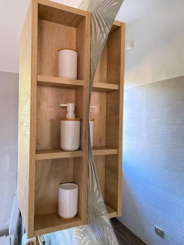 a wooden book shelf with three white cups on it at Olivrea Design Palazzo in Ivrea