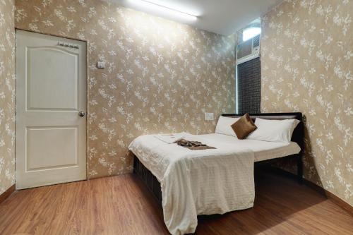 a small bedroom with a bed and a white door at Hotel Shabana - Colaba Causeway in Mumbai