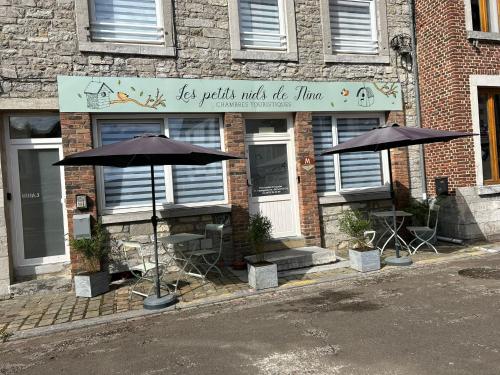 a store with tables and umbrellas outside of it at Les petits nids de Nina 1 in Fosses-La-Ville