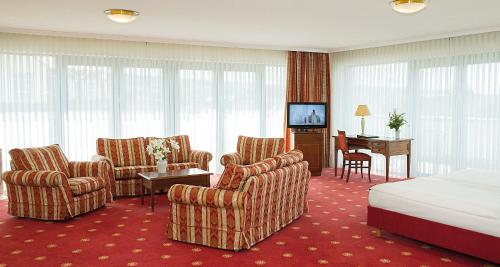 a hotel room with chairs and a bed and a television at Victor's Residenz-Hotel Erfurt in Erfurt