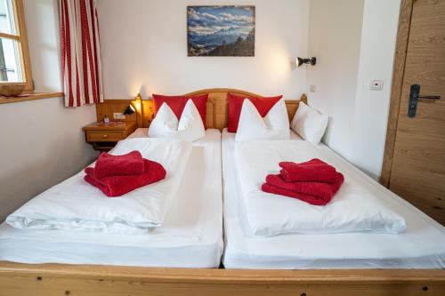 two beds in a room with red pillows on them at Gästehaus Hinterponholz in Ramsau