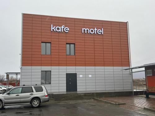 ein Motel-Gebäude mit einem Auto auf einem Parkplatz in der Unterkunft Сарканд in Proletarskiy