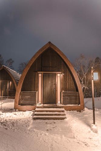 a wooden building with a large door in the snow at Andaru Collection Niseko in Kutchan