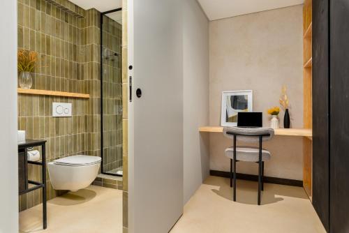 a bathroom with a toilet and a desk with a laptop at Neighbourgood 84 Harrington in Cape Town