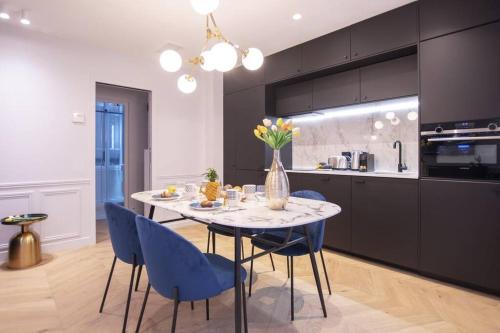 une cuisine avec une table à manger et des chaises bleues dans l'établissement Chic & Fully-Equipped Apartment in Le Marais, à Paris