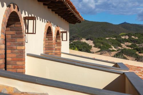 an external view of a house with windows and mountains at Hotel Le Dune Piscinas in Ingurtosu