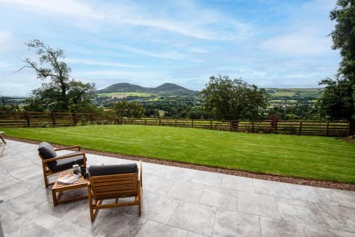 a patio with two chairs and a table and a field at The Sheep Fold in Melrose