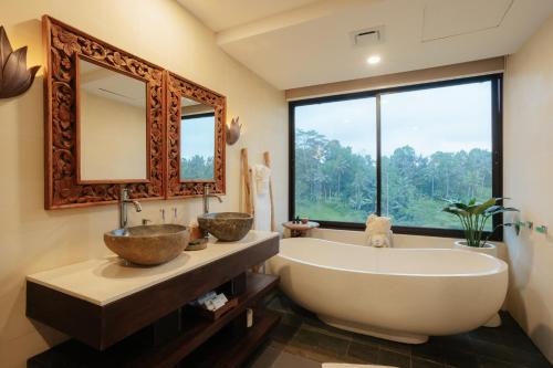 a bathroom with a large tub and a large window at Metland Venya Ubud in Ubud