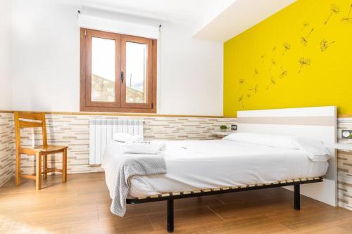 1 dormitorio con cama y pared amarilla en MUNALLA-IDEAL FAMILIAS Y AMIGOS. SENDERISMO. en Aia