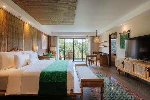 a bedroom with a large bed and a television at Metland Venya Ubud in Ubud