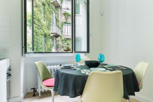 ein Esszimmer mit einem Tisch, Stühlen und einem Fenster in der Unterkunft HL Apartment - Sant'Ambrogio, Duomo in Mailand