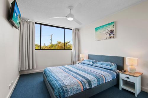 een slaapkamer met een bed en een groot raam bij Allamanda, Unit 11, 32 Esplanade, Bulcock Beach in Caloundra