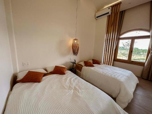two beds in a room with a window at Country Road Villa in Xuyên Mộc