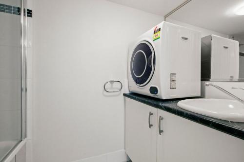 een badkamer met een wastafel en een wasmachine bij Allamanda, Unit 11, 32 Esplanade, Bulcock Beach in Caloundra